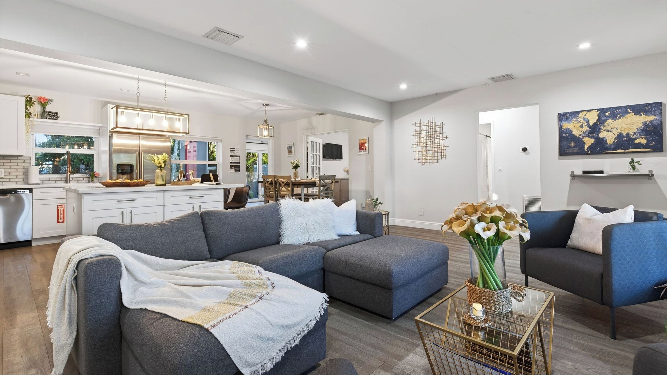 A modern living room with a grey sectional sofa, a coffee table, and a dining area in the background.