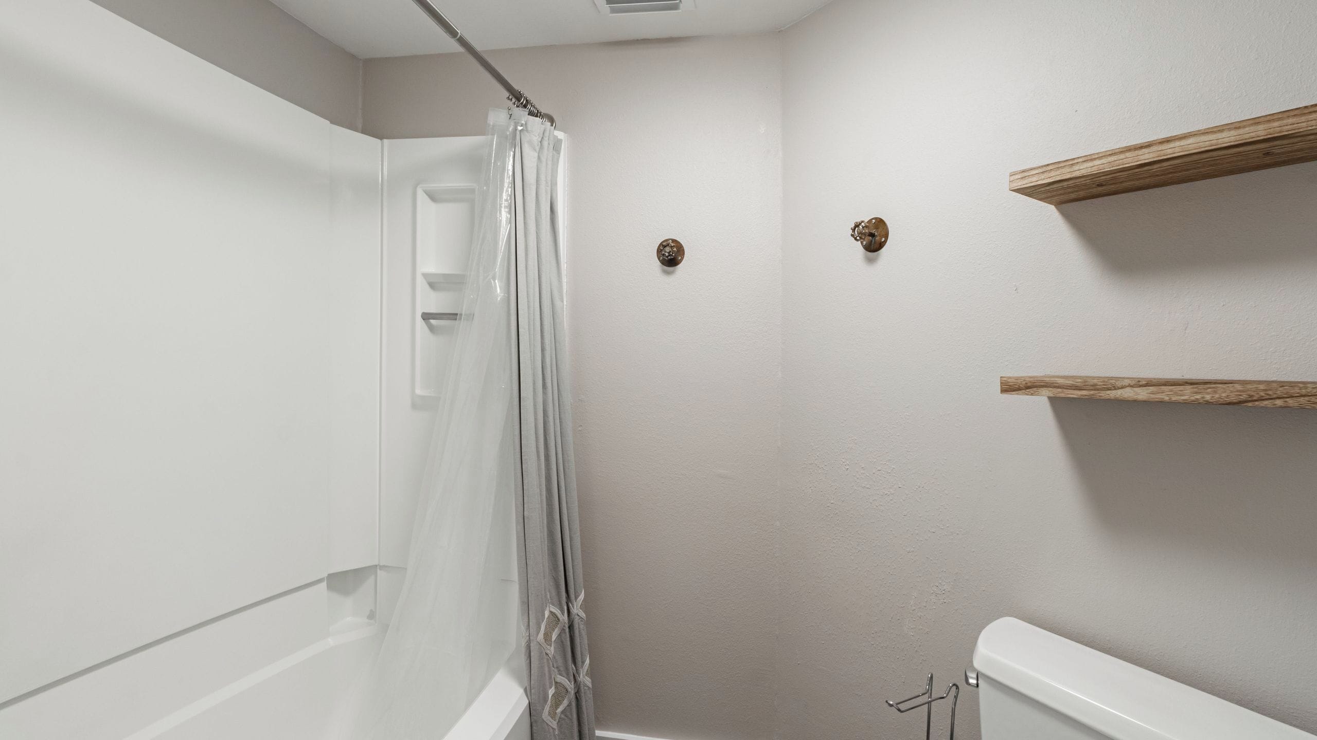 Une salle de bain équipée d’une douche, de toilettes et d’une étagère fixée au mur.