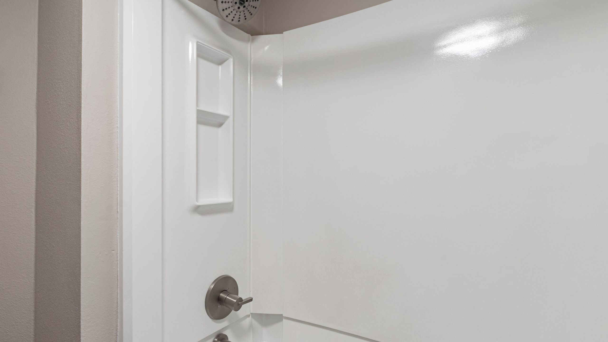 Een badkamer met een witte deur, een klein schap en een wastafel.