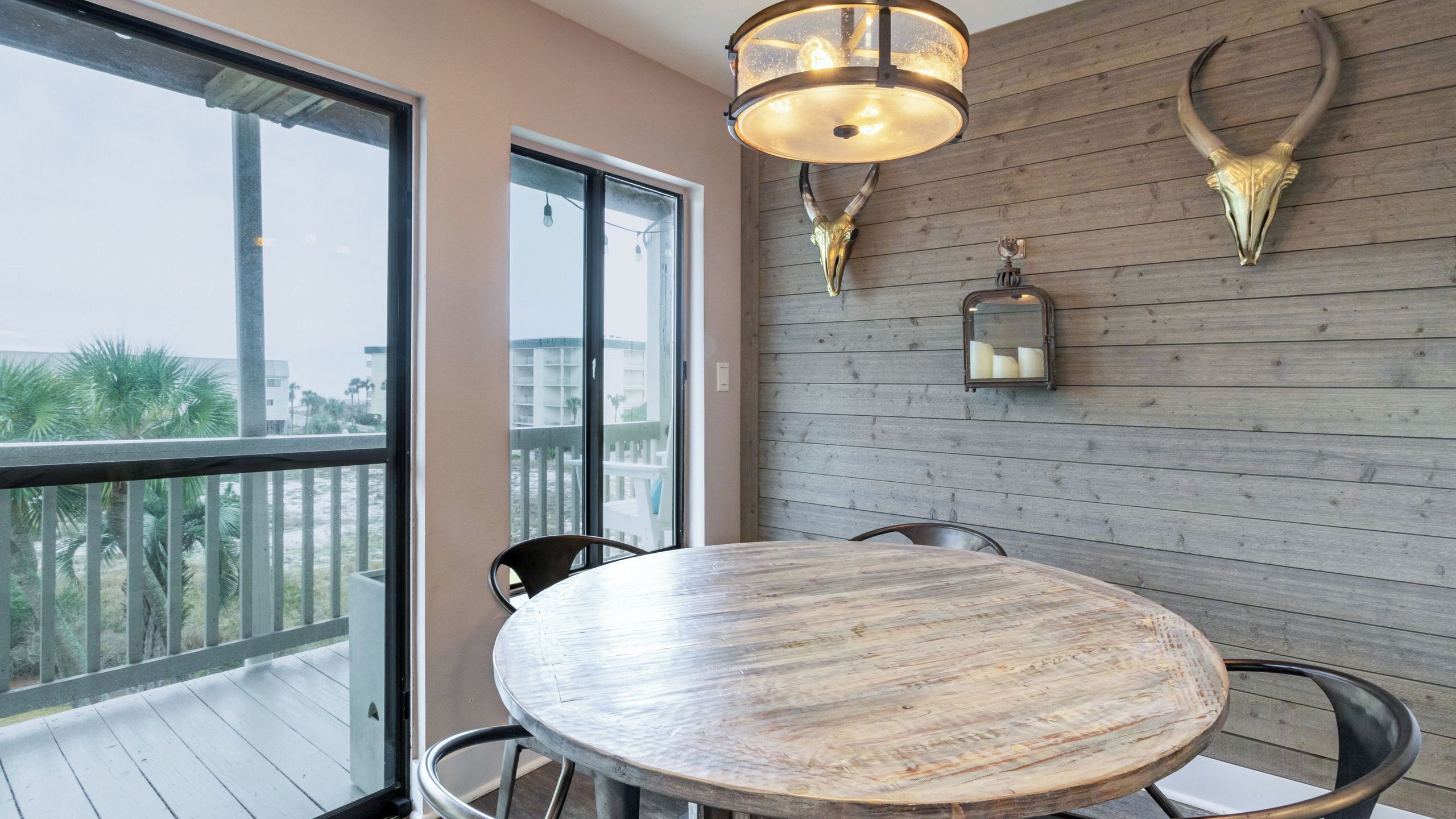 Ein Balkon mit rundem Tisch und Stühlen, eine Holzvertäfelung mit aufgehängtem Horn und einer Pendelleuchte.