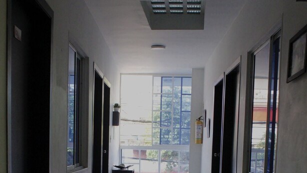 A hallway with a bed, a suitcase, and a fire extinguisher. - Hotel los magueyes  (Bucaramanga)