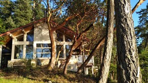 Ett modernt hus med ett sluttande tak, stora fönster och en veranda.