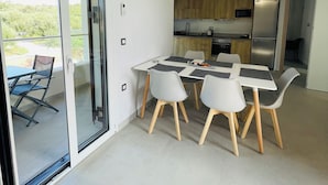 A modern kitchen with a dining area, featuring a sliding glass door to a balcony, a built-in oven, and a refrigerator. - Room-villa Rodelia Apartment Number 4 (Corfu)