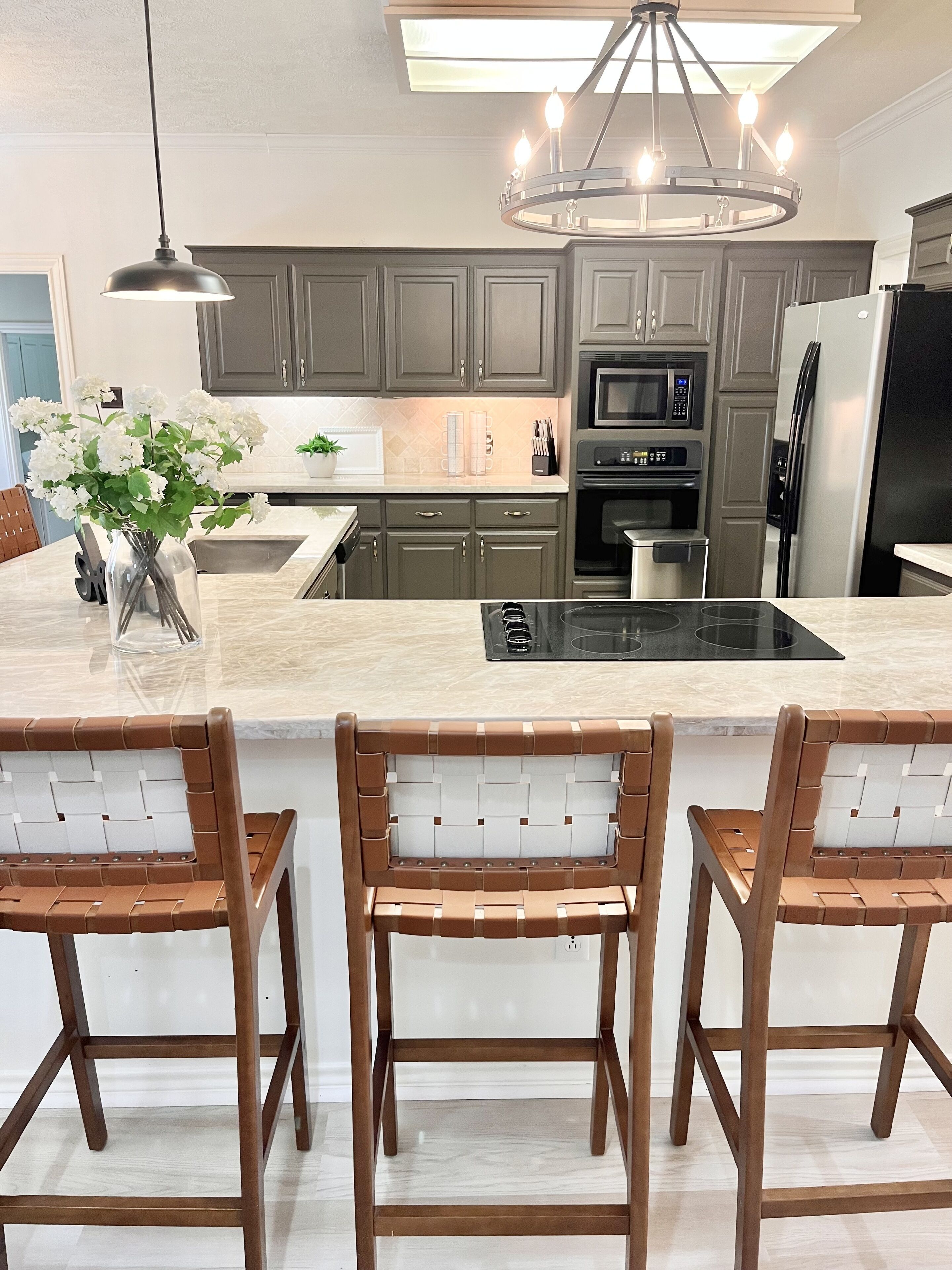 A modern kitchen with a central island, built-in appliances, and a pendant light.