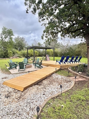 A wooden deck with outdoor seating, a pergola, and a flag.