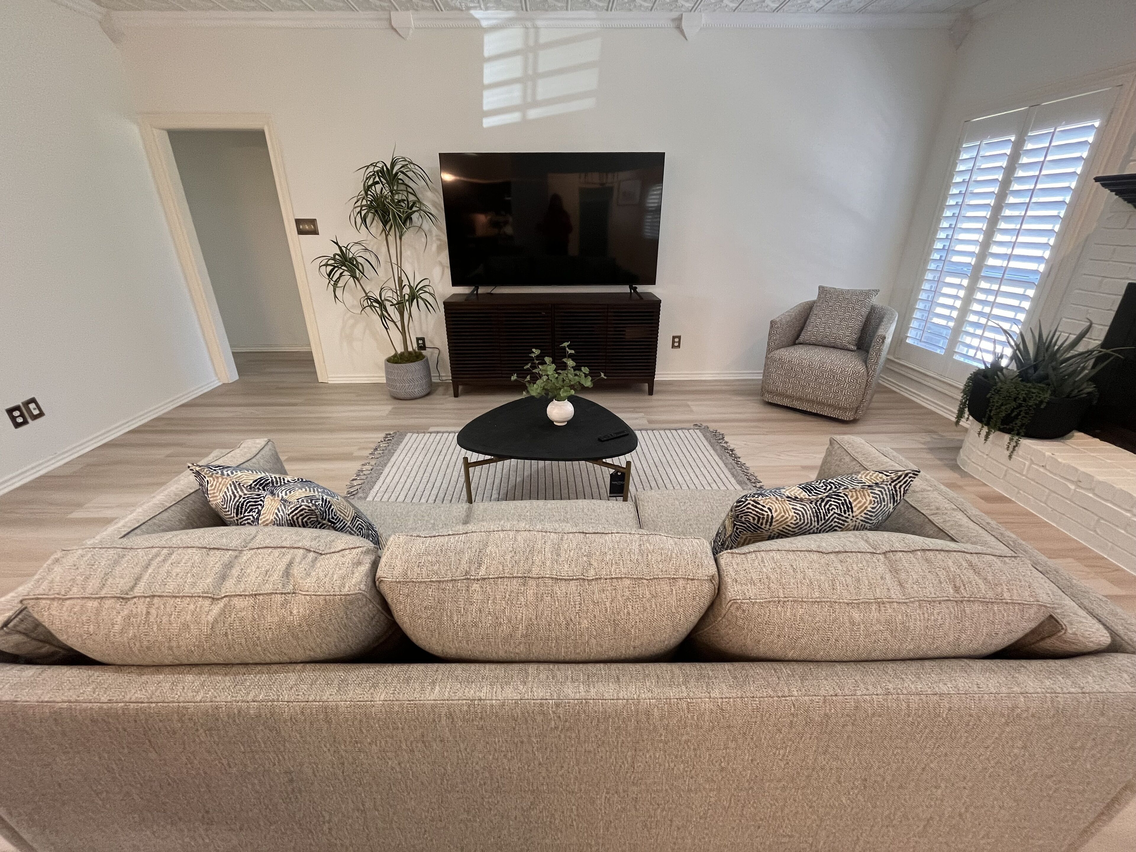 A modern living room with a sectional sofa, a coffee table, a flat-screen TV, and a fireplace.