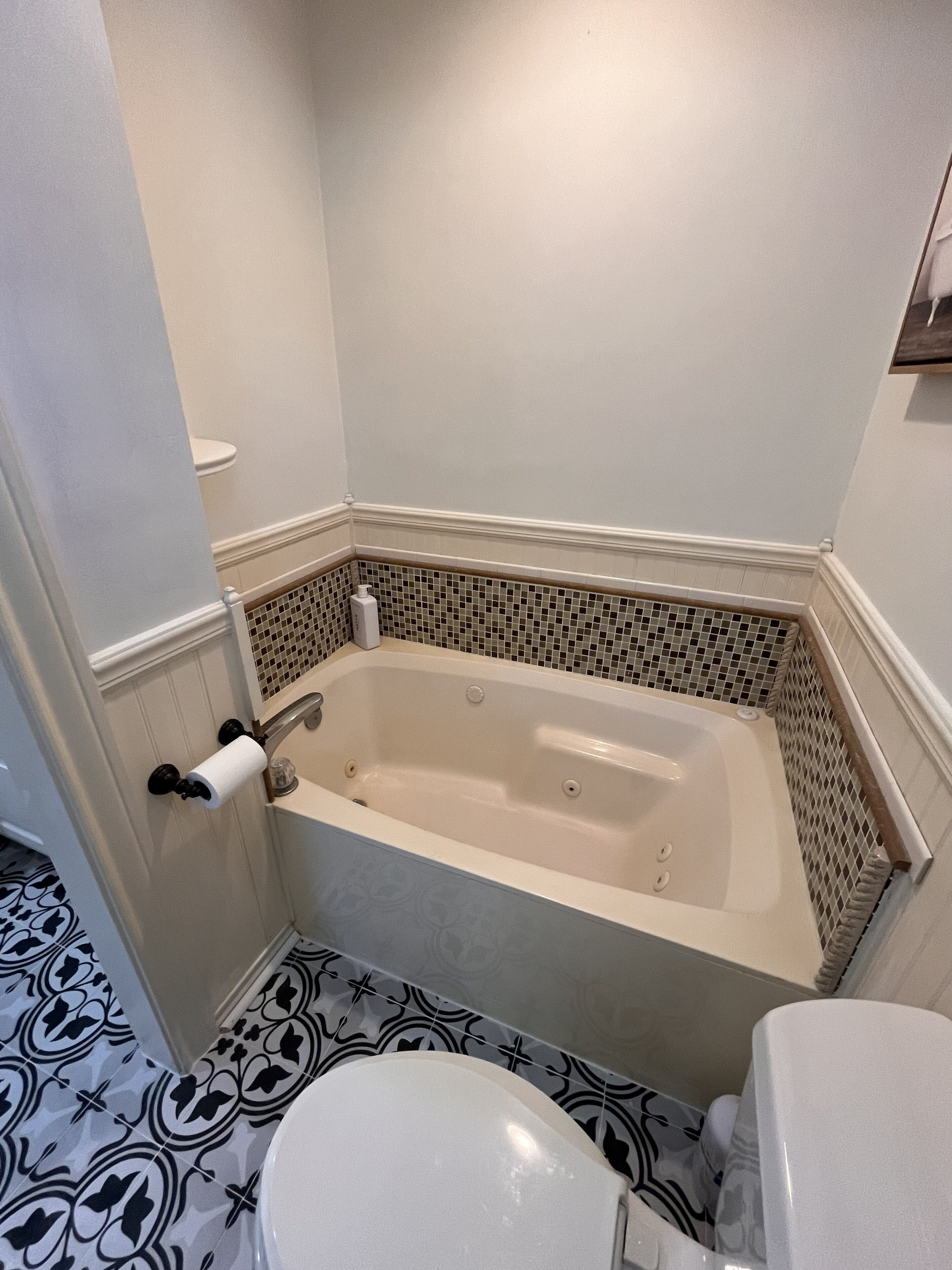 Ein Badezimmer mit Badewanne, Toilette und fußbodenhohen, gemusterten Fliesen.