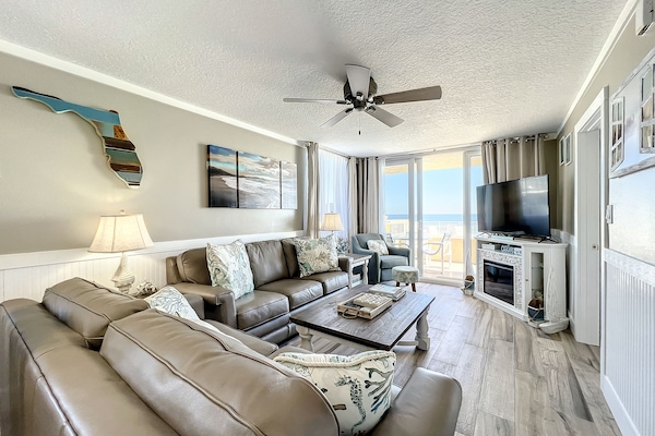 This beautifully decorated living room features plush seating, modern décor, and large windows offering breathtaking ocean views, perfect for relaxation and enjoying coastal vibes.