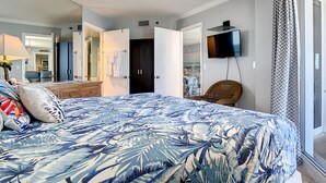 A bedroom with a bed, a television, a chair, and a wardrobe. - Direct Oceanfront Condo - Pool, Beach & Steps from Flagler Ave (New Smyrna Beach)