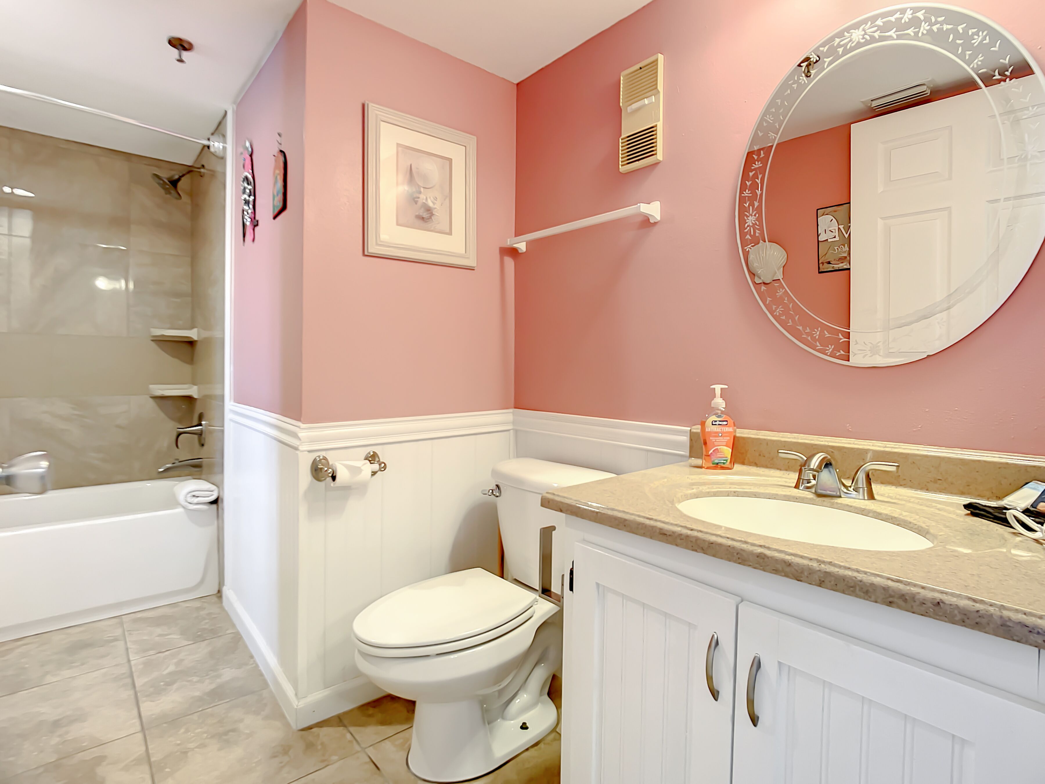 Un baño con bañera, inodoro y tocador con lavabo.