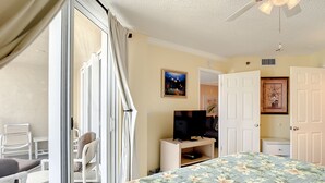 A bedroom with a bed, a TV, a desk, and a chair.