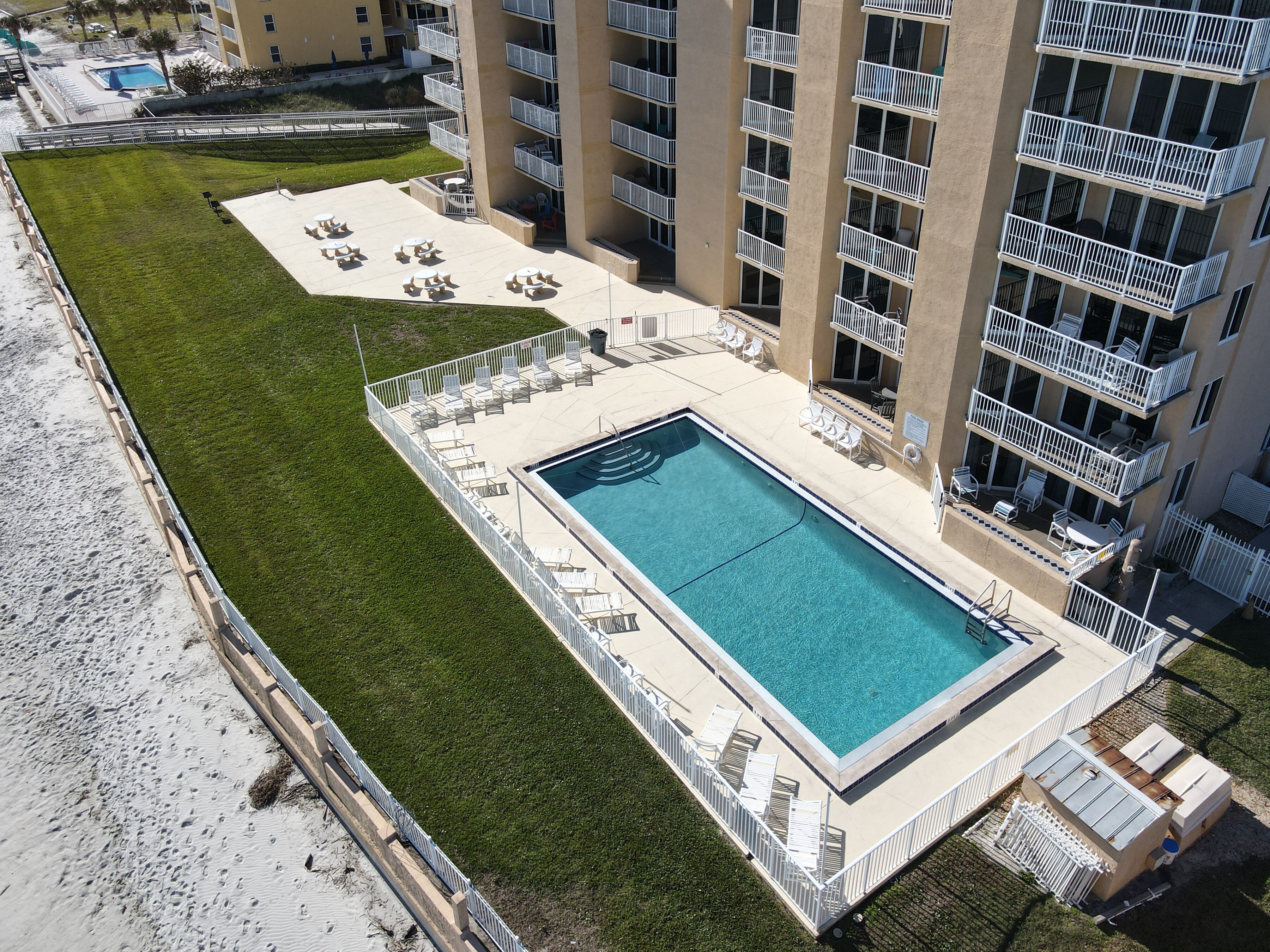 A rooftop pool with lounge chairs and a view of a high-rise building.