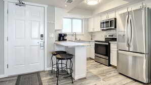 A modern kitchen with white cabinetry, stainless steel appliances, a built-in microwave, and a coffee maker.
