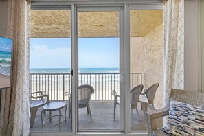 Un balcon avec vue sur la plage, un canapé en osier et deux fauteuils.
