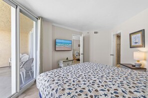 Quarto com cama, televisão, escrivaninha e cadeira.