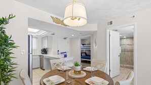 Un espace repas comprenant une table ronde, des chaises et un luminaire suspendu au plafond.