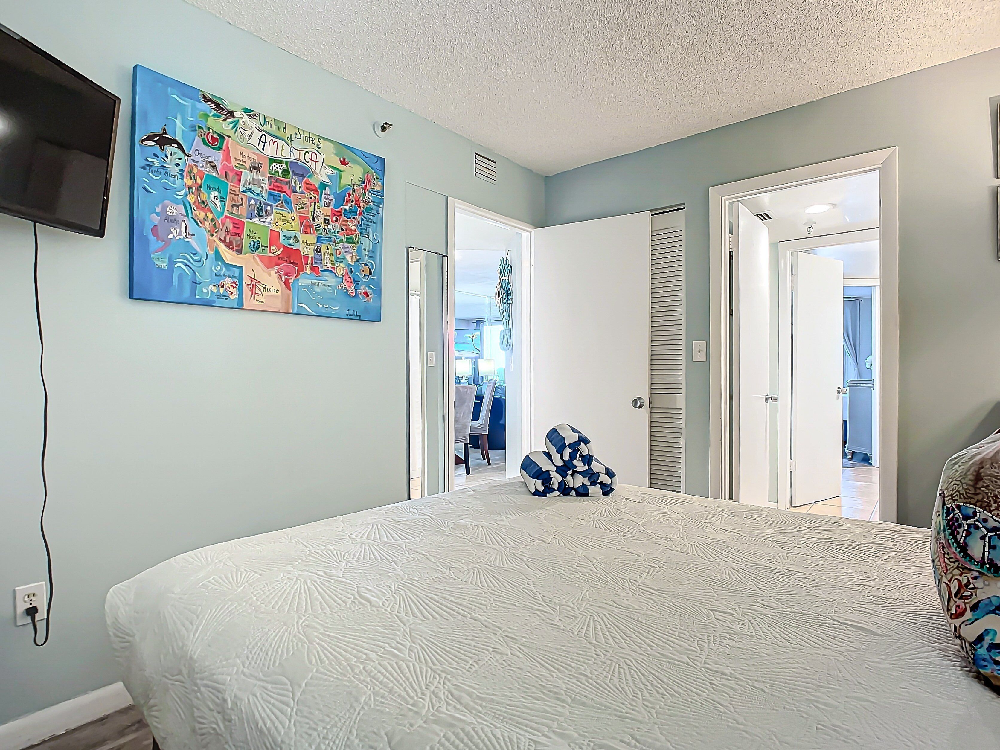 A bedroom with a large bed, a map on the wall, and a TV mounted on the wall.