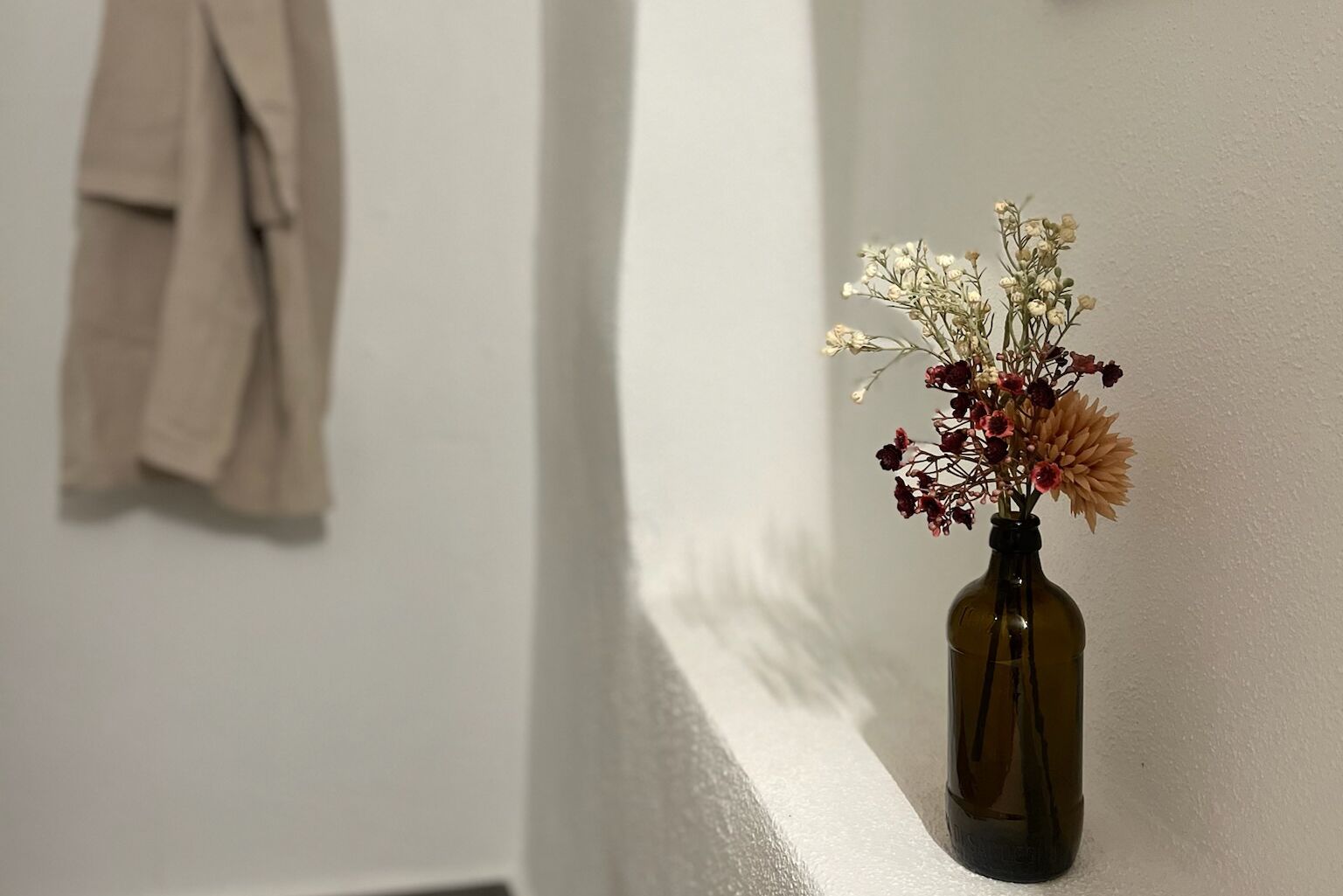 Eine Vase mit getrockneten Blumen an einer weißen Wand.