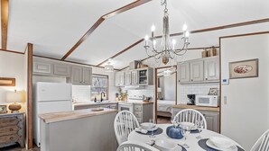 A compact kitchen with a central island, white cabinetry, and a chandelier.