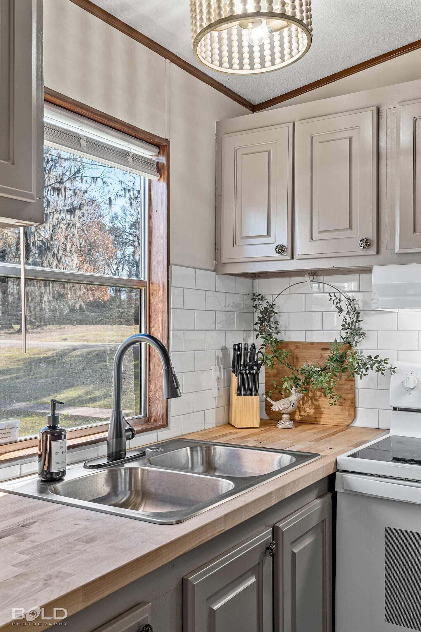 Cocina moderna con un lavamanos doble, encimera de madera y vistas al exterior.