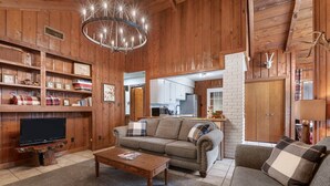 Una sala de estar acogedora con detalles de madera, un televisor sobre un mueble de madera, un sofá y una mesa de centro.