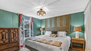 A bedroom with a large bed, two bedside tables, a wooden wardrobe, and a window with curtains.