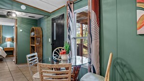 A dining area with a glass table, wicker chairs, and a view of the outdoors.