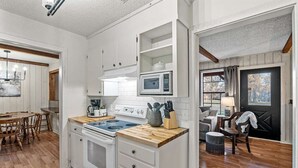 Una cocina con armarios blancos, microondas, estufa y encimera de madera.