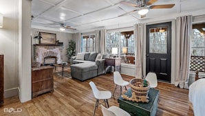 A spacious living room with a fireplace, a sofa, a coffee table, and a dining area with chairs. - Lakefront cabin with sweeping views of Caddo Lake, lakeside to the pier and kayaks, plus a foosball table for fun downtime. (Karnack)