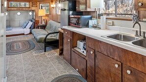 A compact kitchen with wooden cabinets, a built-in refrigerator, and a window with a view of trees. - Unforgettable Experience: Enjoy a maritime adventure unlike any other. Unwind in a cozy little ship with upper and lower decks with private dock access (Karnack)