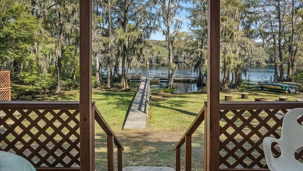 A wooden deck with a view of a lake, surrounded by trees and a dock. - Southern Pearl is all about simple, peaceful lake living. Wake up to water views, spend your days kayaking or canoeing, and wind down with quiet evenings by the water. (Karnack)