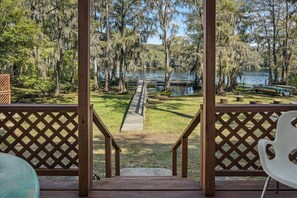 A wooden deck with a view of a lake, surrounded by trees and a dock. - Southern Pearl is all about simple, peaceful lake living. Wake up to water views, spend your days kayaking or canoeing, and wind down with quiet evenings by the water. (Karnack)