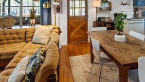 A cozy living room with a brown sofa, a wooden dining table, and a kitchen with blue cabinets. - Southern Pearl is all about simple, peaceful lake living. Wake up to water views, spend your days kayaking or canoeing, and wind down with quiet evenings by the water. (Karnack)