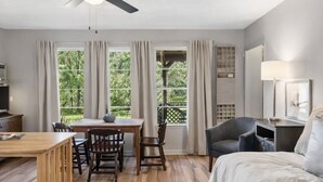 A hotel room with a bed, a desk, a chair, a ceiling fan, and large windows with curtains. - Southern Pearl is all about simple, peaceful lake living. Wake up to water views, spend your days kayaking or canoeing, and wind down with quiet evenings by the water. (Karnack)