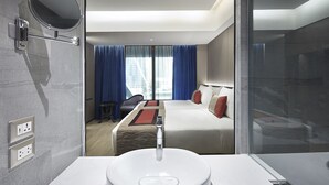 Une chambre d’hôtel moderne, dotée d’un grand lit, d’un bureau et d’une salle de bain avec un lavabo et un miroir.