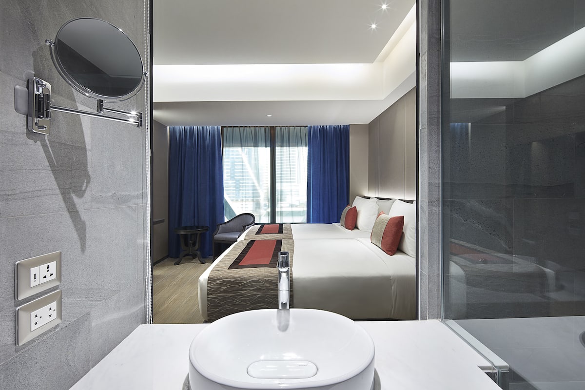 Une chambre d’hôtel moderne, dotée d’un grand lit, d’un bureau et d’une salle de bain avec un lavabo et un miroir.