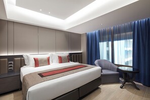 A modern hotel room with a large bed, a seating area, and a view of the city through large windows. - Grace At Five By Grace Hotel (Bangkok)