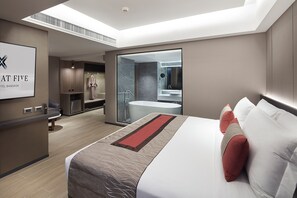 A modern hotel room with a large bed, a bathroom with a bathtub, a shower, and a vanity. There is a desk with a chair and a large window. - Grace At Five By Grace Hotel (Bangkok)