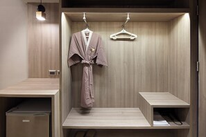 Un baño moderno con un tocador de madera, una bata colgada de un gancho y un perchero blanco.
