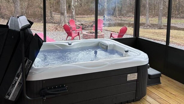 A hot tub in a covered outdoor area with a view of a forest. - Tiny Cajun Cabin (Breaux Bridge)