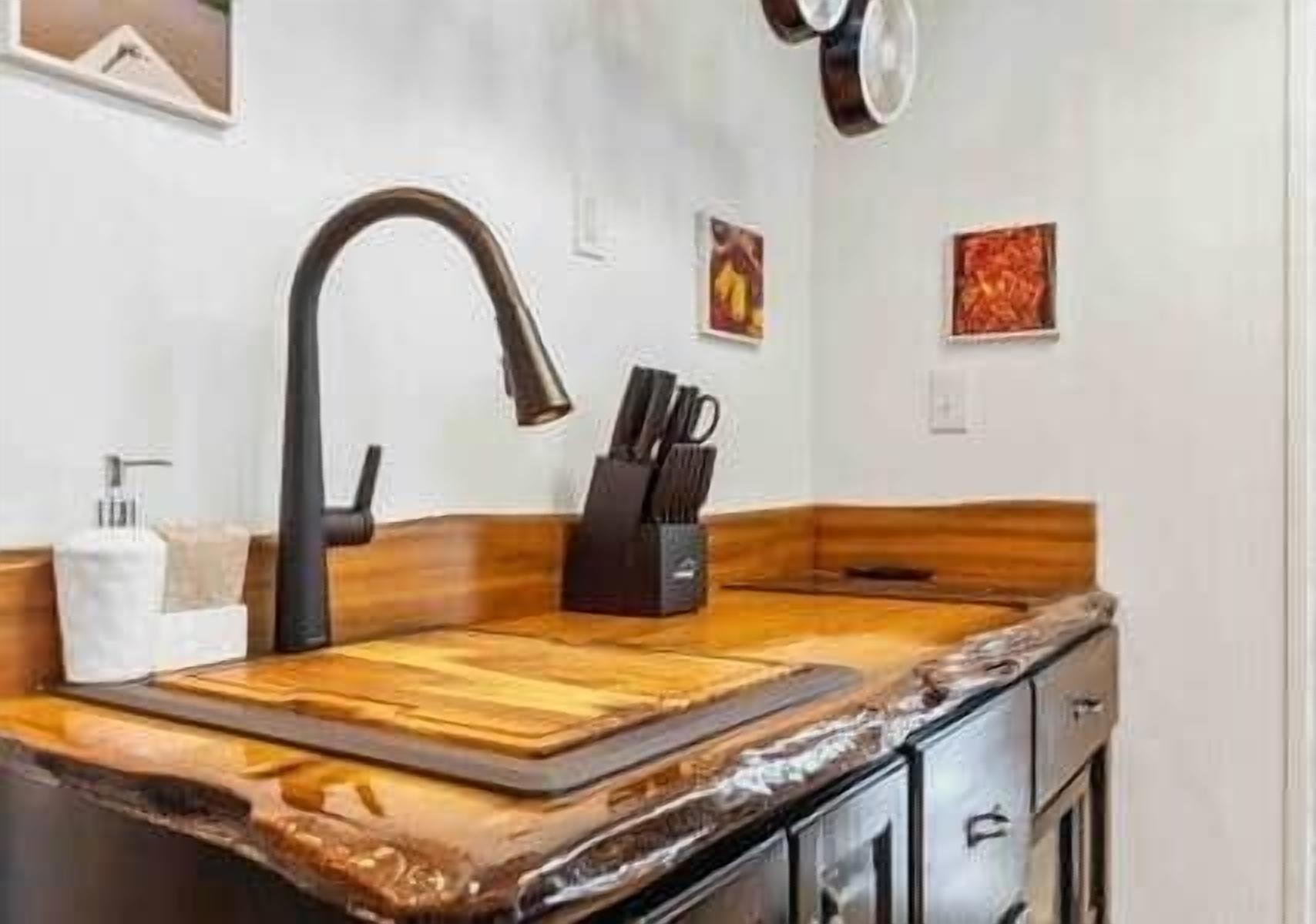 Une cuisine dotée d’un plan de travail en bois, d’un robinet noir et d’un bloc à couteaux.