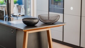 Une cuisine moderne avec une table en bois, deux bols et un réfrigérateur en acier inoxydable.