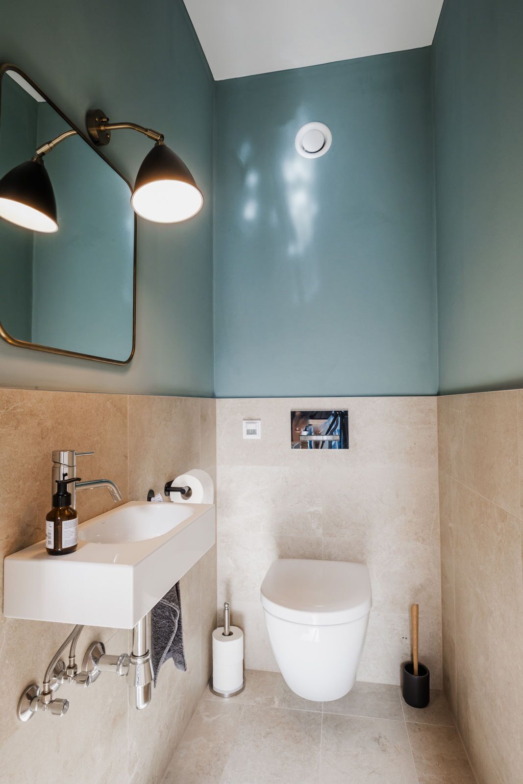 Un baño moderno con lavamanos blanco, espejo, inodoro y ducha.