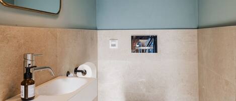 Un baño moderno con lavamanos blanco, espejo, inodoro y ducha.