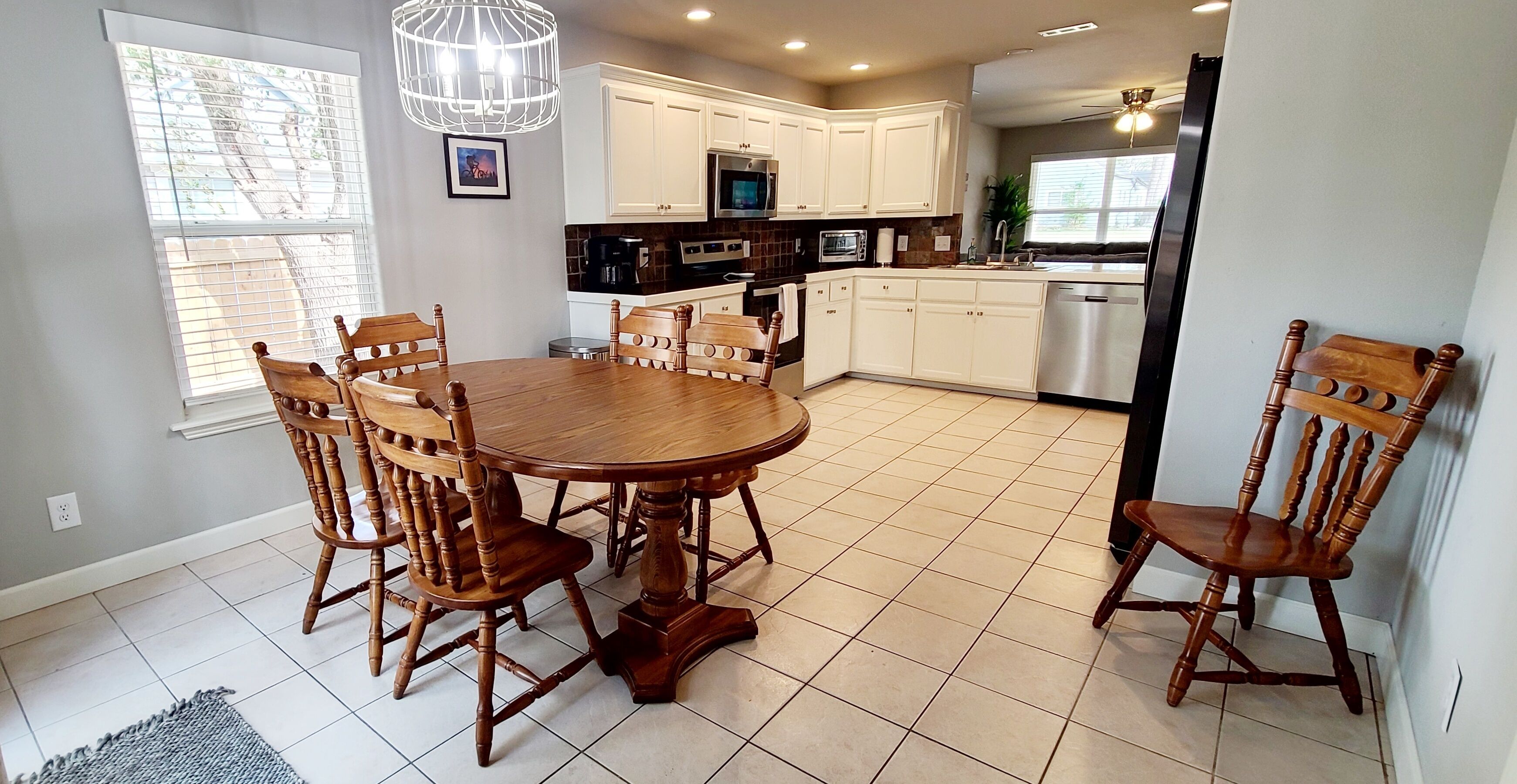 Una cocina moderna con armarios blancos, una mesa redonda de madera y seis sillas de madera.