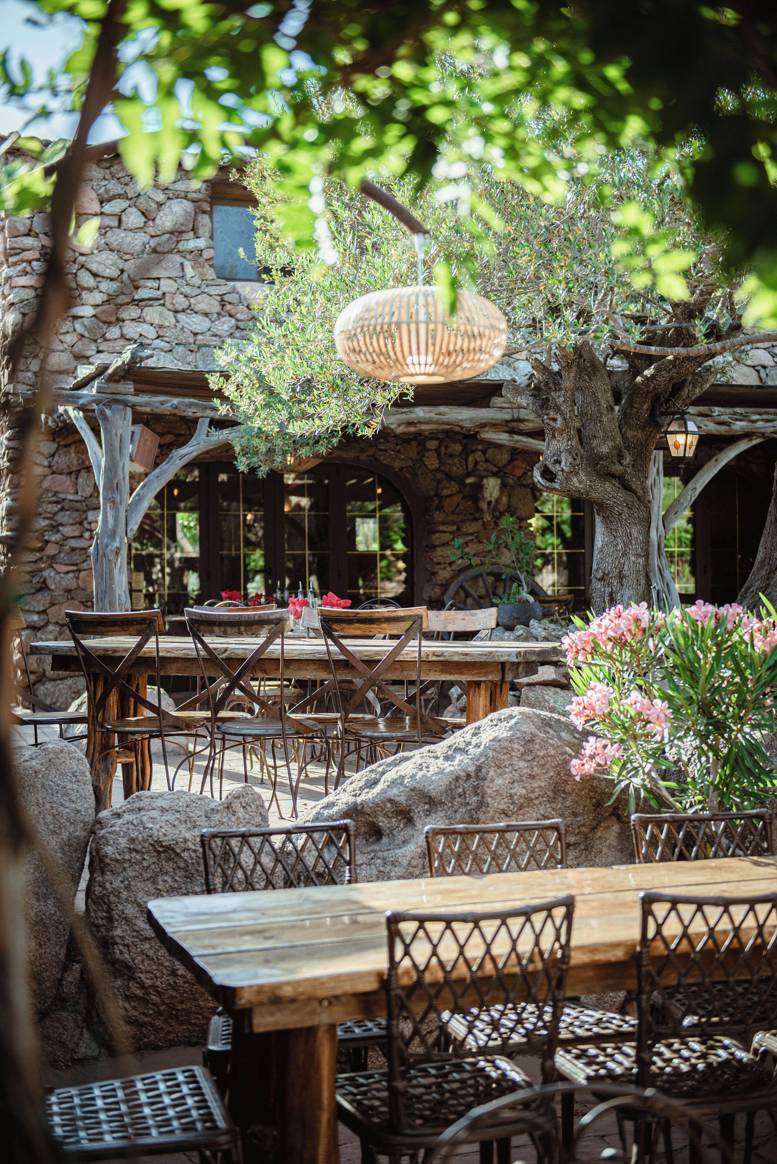 Un espace extérieur aménagé pour les repas, avec des murs en pierre, des tables et des chaises en bois.