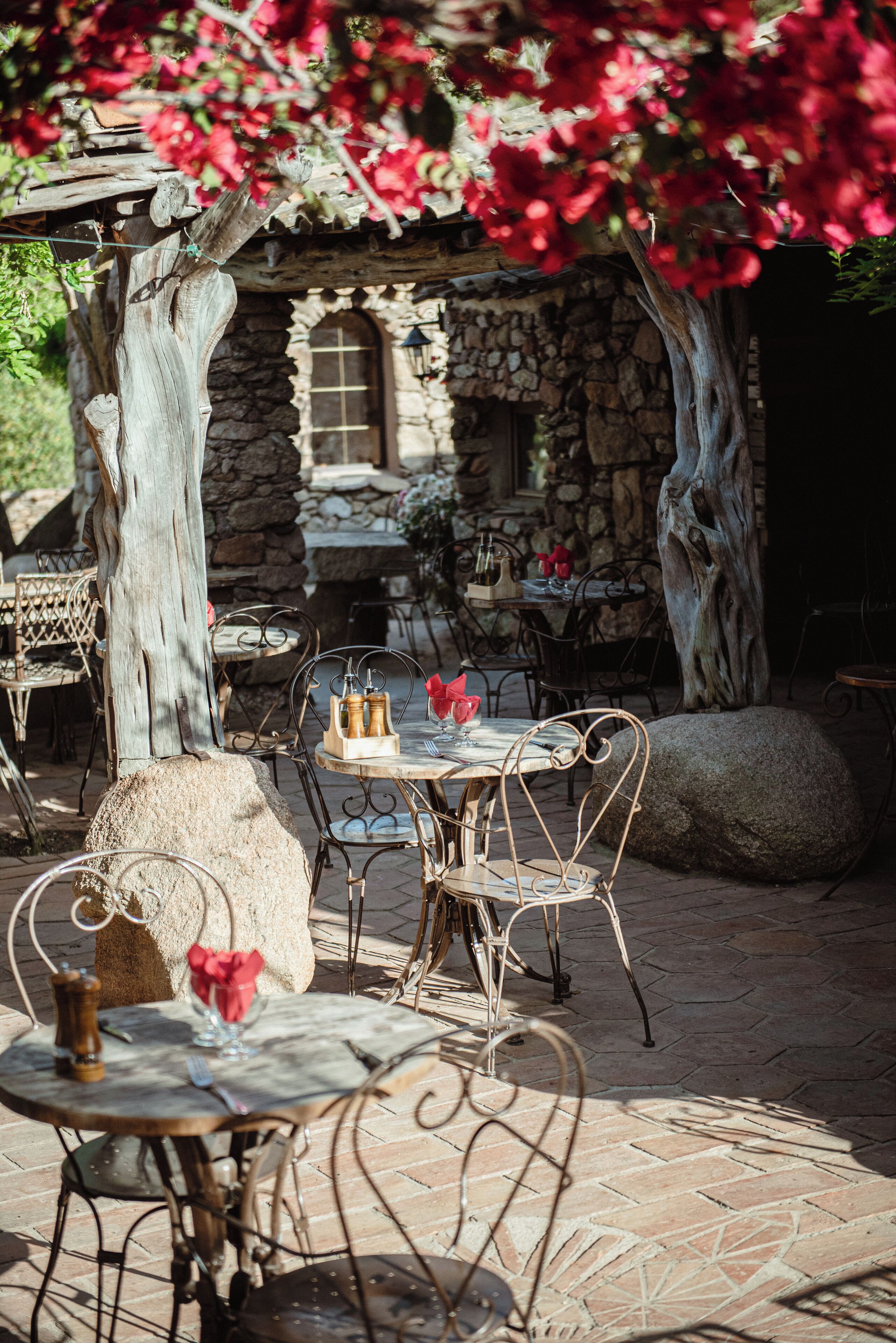 An outdoor patio with stone walls, metal chairs, and tables.