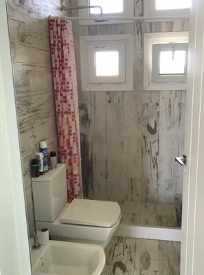 Bathroom features a shower area, toilet, and marble-like flooring.