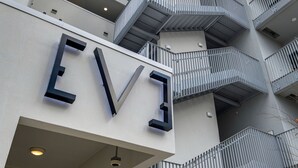En bygning med et tydeligt ’EV’-skilt, flere balkoner og moderne arkitektur.