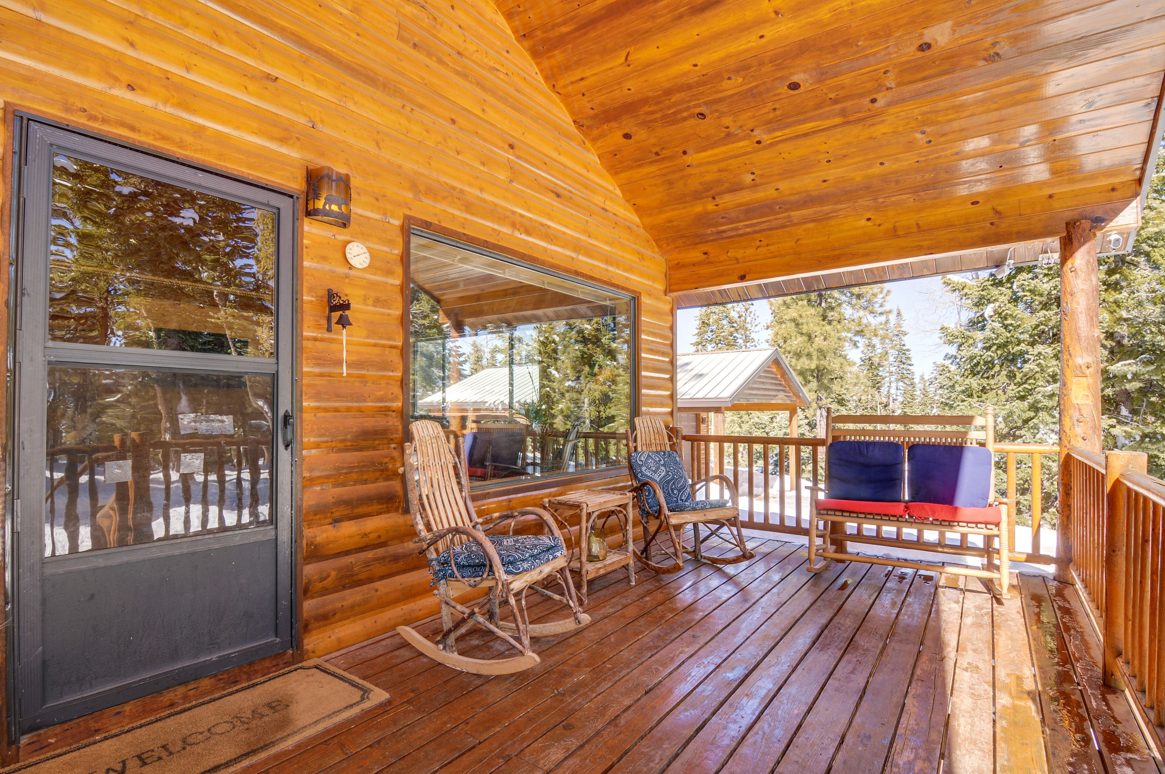 A wooden cabin with a porch featuring rocking chairs and a bench.